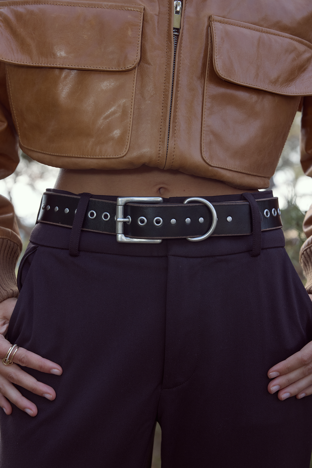 Close-up of the Frankie black vintage belt on model, showing moto grommets and hardware.