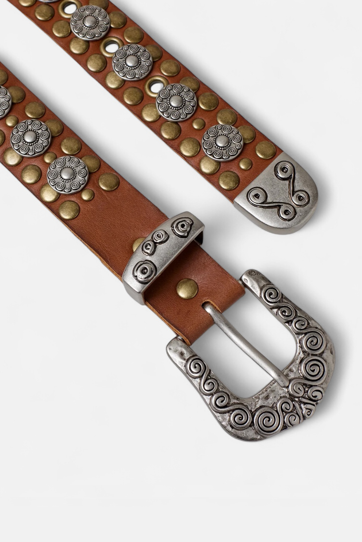 Zoomed in flat lay of the Marlowe cognac studded leather belt with ornate silver floral hardware visible.