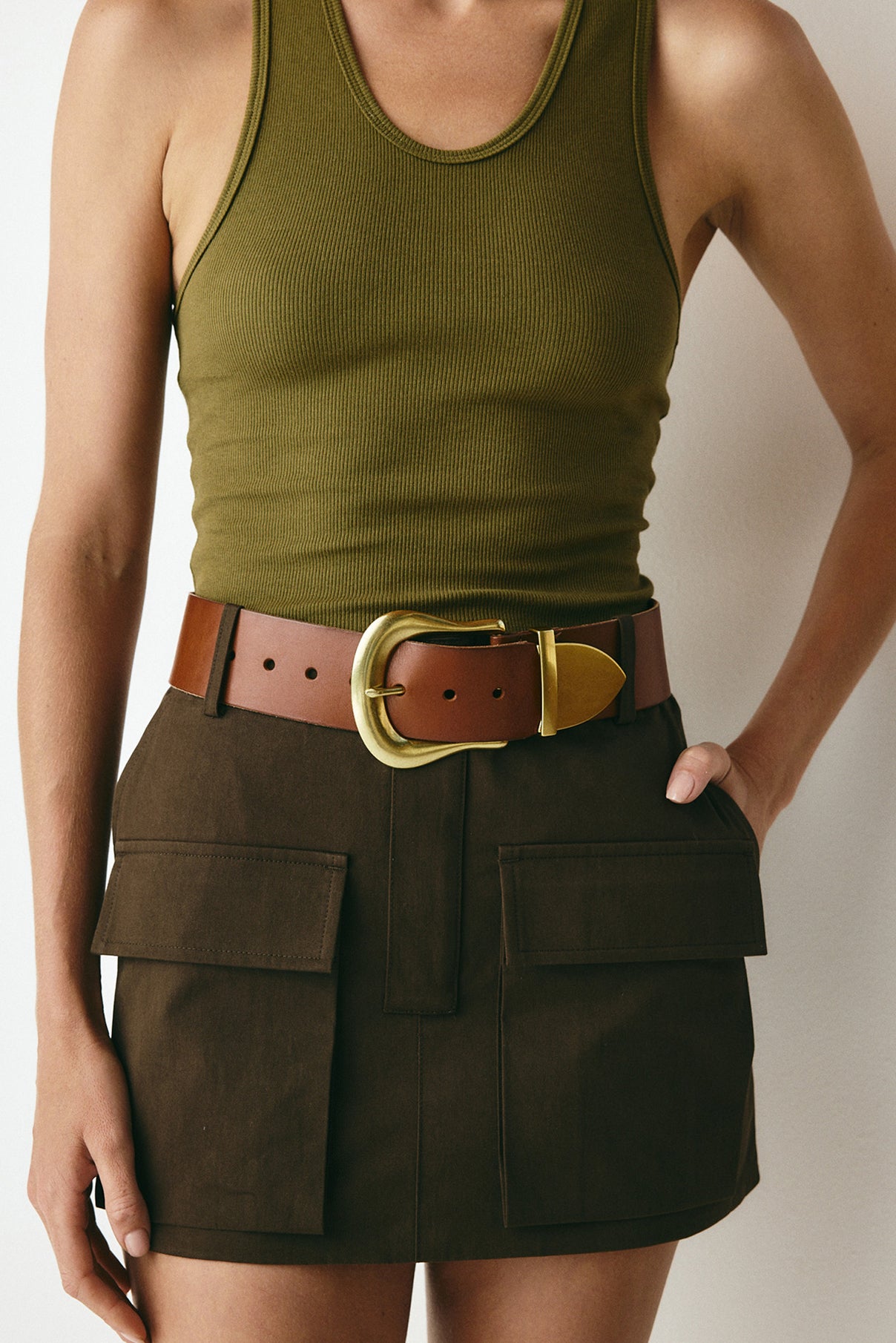 Close-up of the Maylee cognac belt worn on the model, highlighting gold buckle detail.