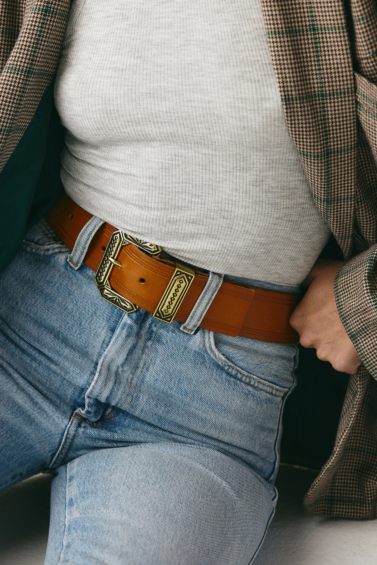 Close-up view of the Nola vachetta belt on model, showcasing gold hardware detail.